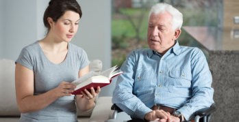 elderly man and caregiver reading a book
