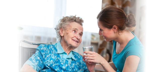 caregiver assisting senior woman in drinking water